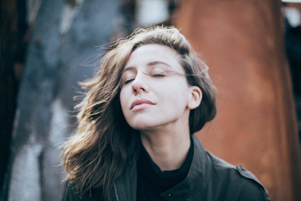 A woman closes her eyes and the wind blows her hair in her face.