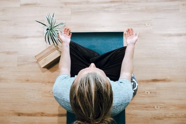 A person meditates in a yoga pose for holistic wellness.