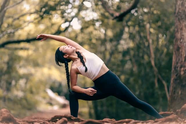 A woman does yoga in the woods.