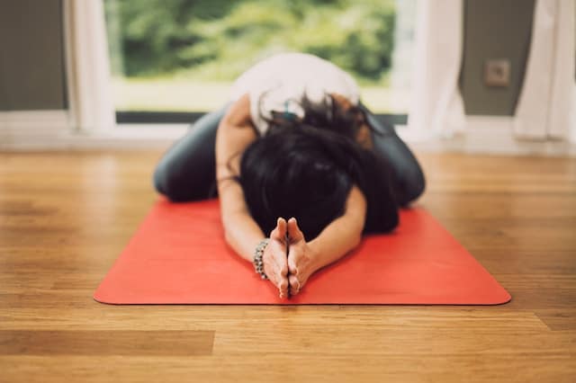 A woman lays face down on her yoga mat.