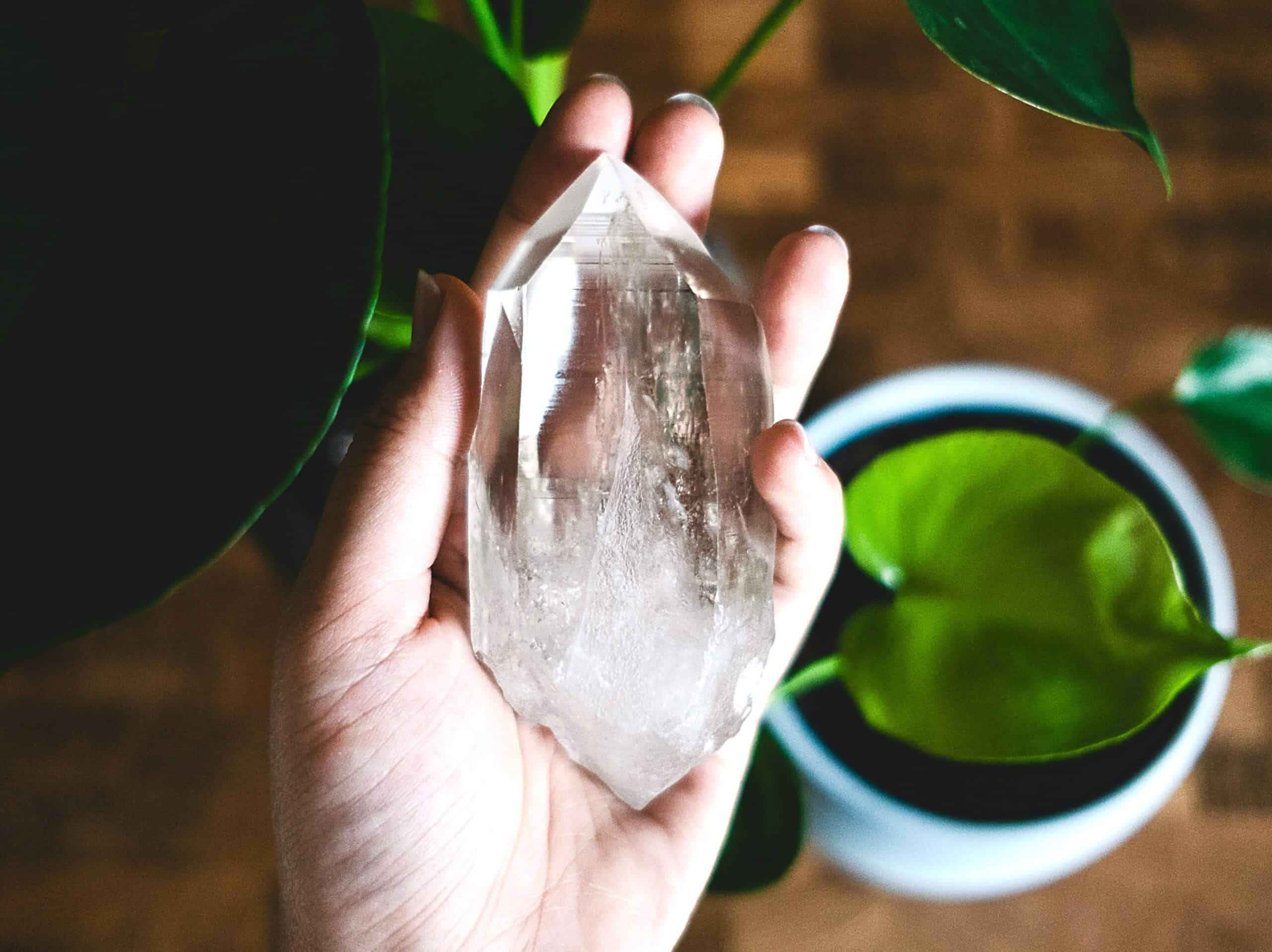 A hand holds a clear quartz crystal