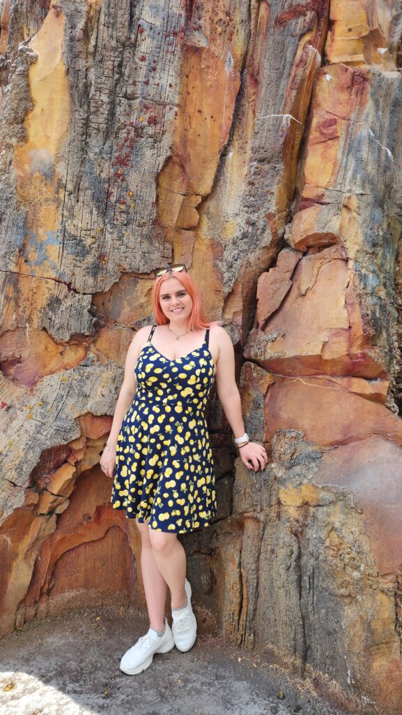 A woman stands against a rugged rock wall.