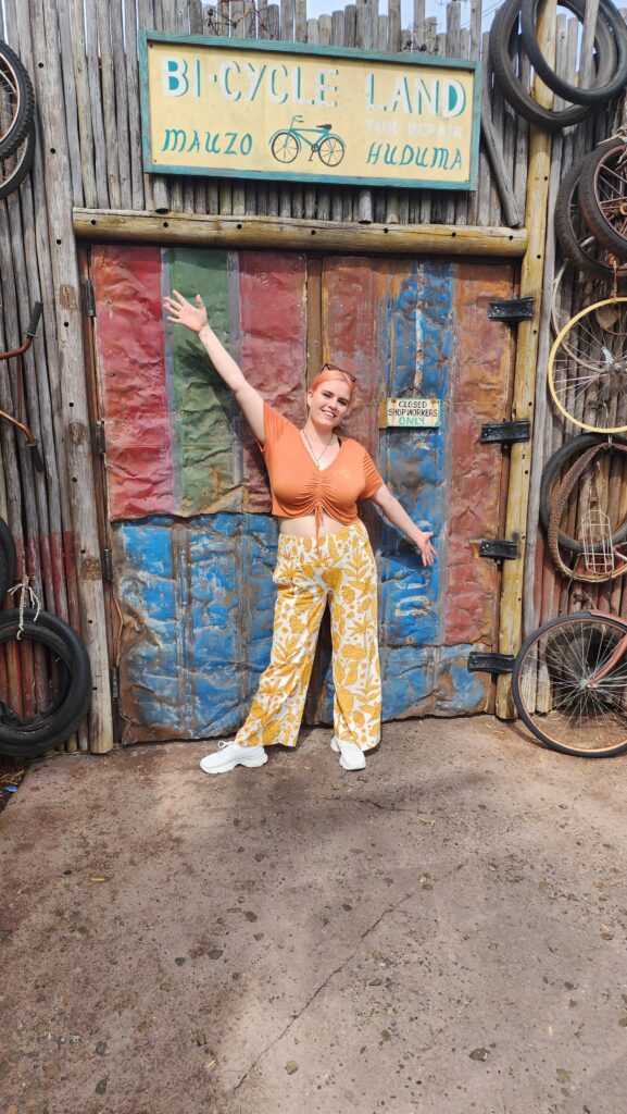 A woman stands in front of a colorful wall with bike tires.