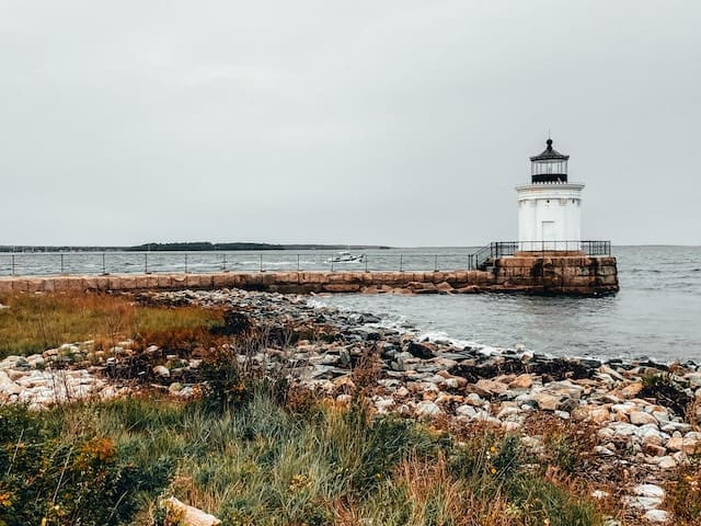 A squat lighthouse sits next to the ocean.