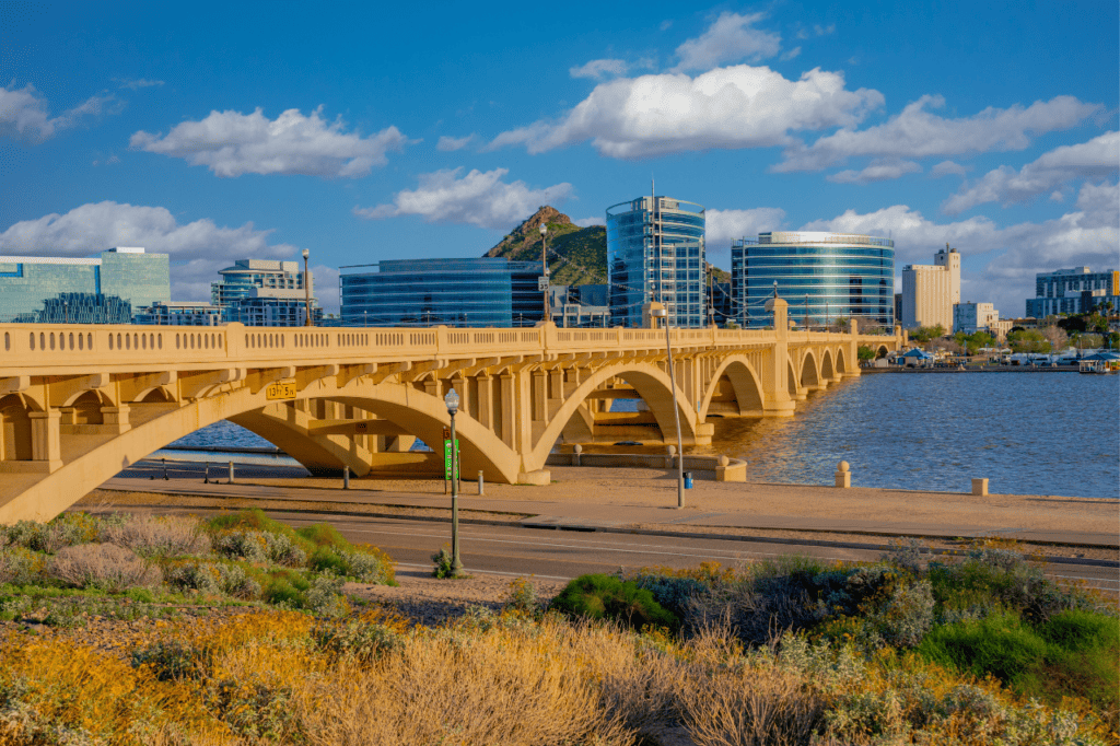 A bridge crosses over a body of water, glass buildings stand in the distance.