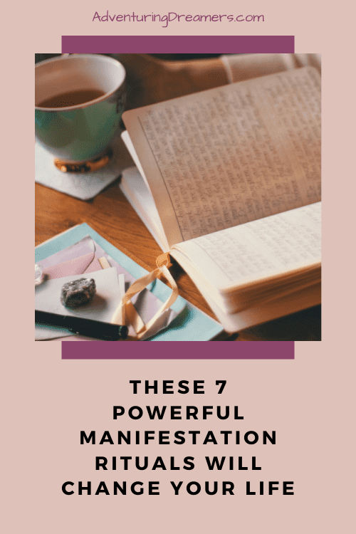 A person reads a book in one hand and a tea cup in the other. Next to the book on the table are a pile of colored envelopes with a crystal on top as a paper weight. Text below the image reads, "These 7 powerful manifestation rituals will change your life."