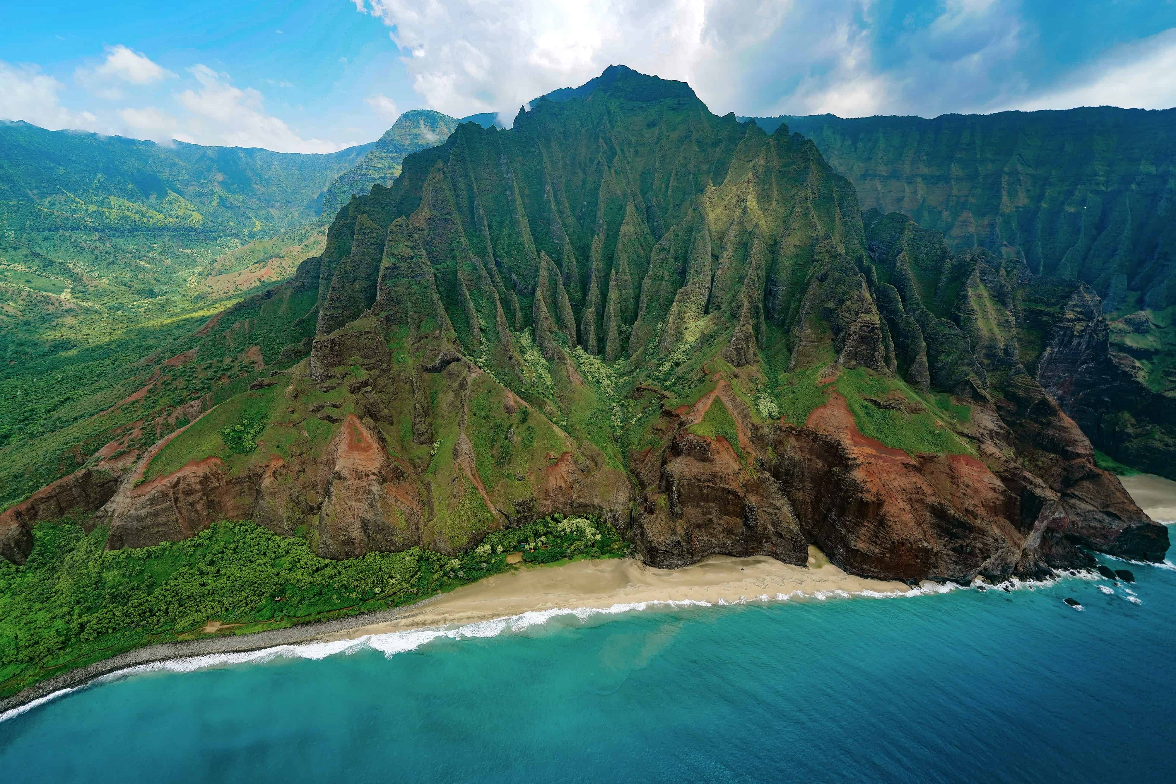 A stunning red mountain covered in lush greenery on the coast of an island.