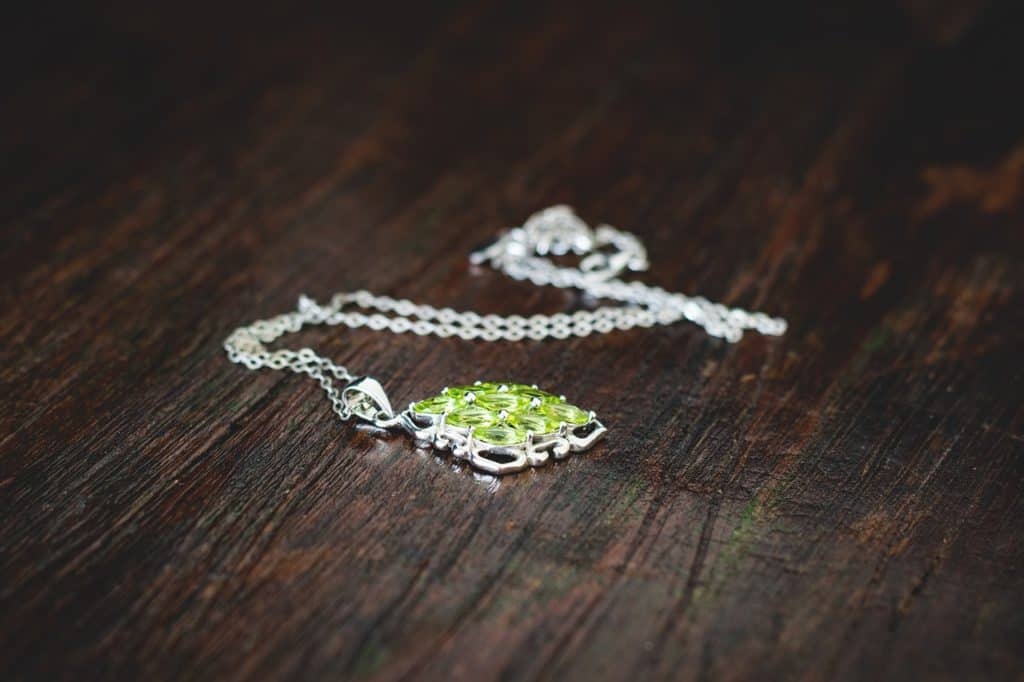 A green and silver necklace on a table.