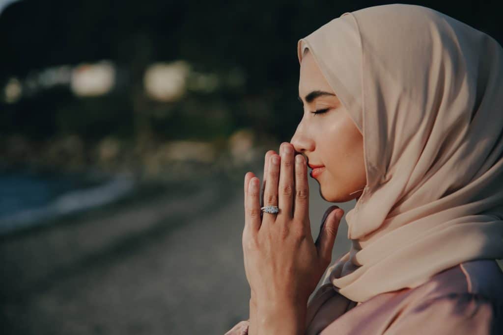 Woman with eyes closed, hands pressed against her lips in thanks