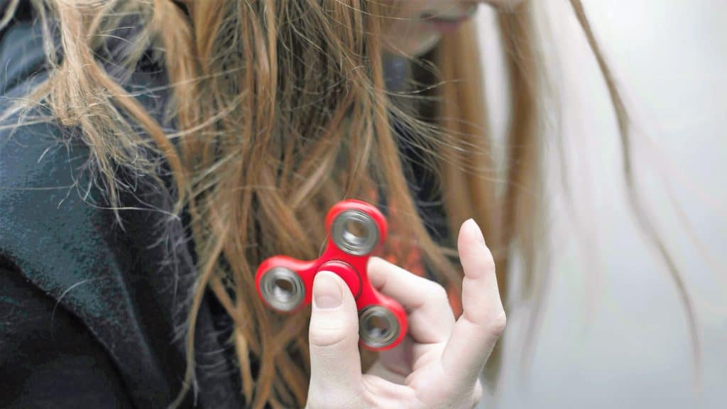 A woman holds a red fidget spinner.