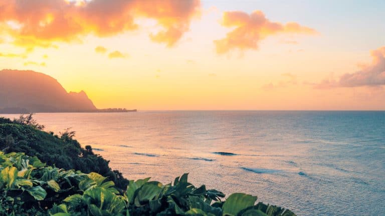 A view of the ocean from the coast of an island at sunset.