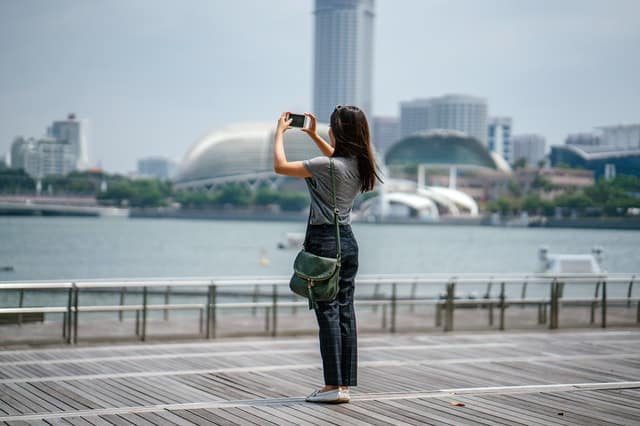 A woman takes a picture of scenery with her phone.