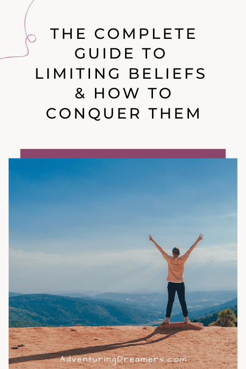 A person stands with their arms raised above their head, hands showing the peace sign, looking out over a mountain cliff. Text reads: The complete guide to limiting beliefs & how to conquer them. Adventuringdreamers.com