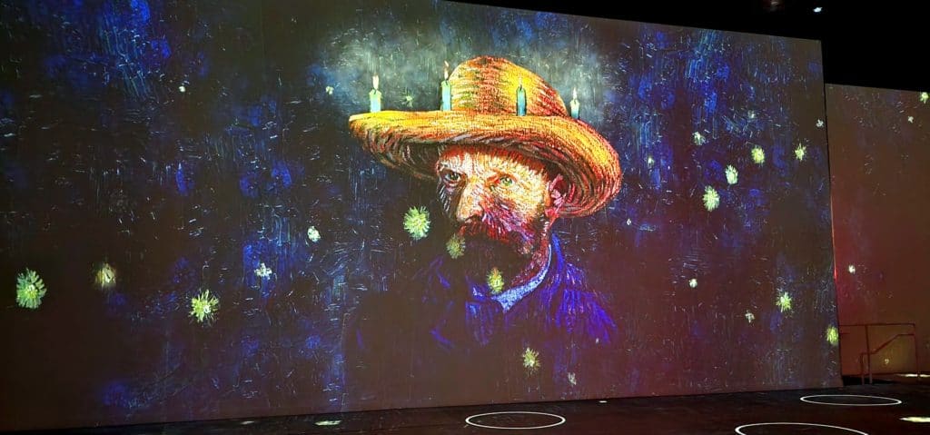 Van Gogh's painting of a man with candles on his hat is projected onto a wall.