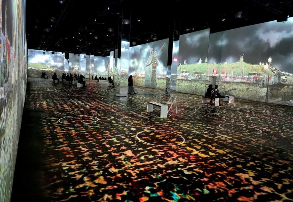 A large room has projected images of a Van Gogh painting on the walls and floor.