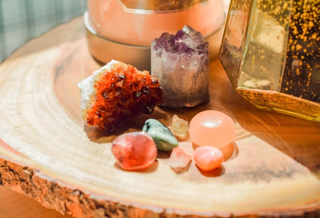 A cluster of mixed stones and crystals are on a brightly lit table.