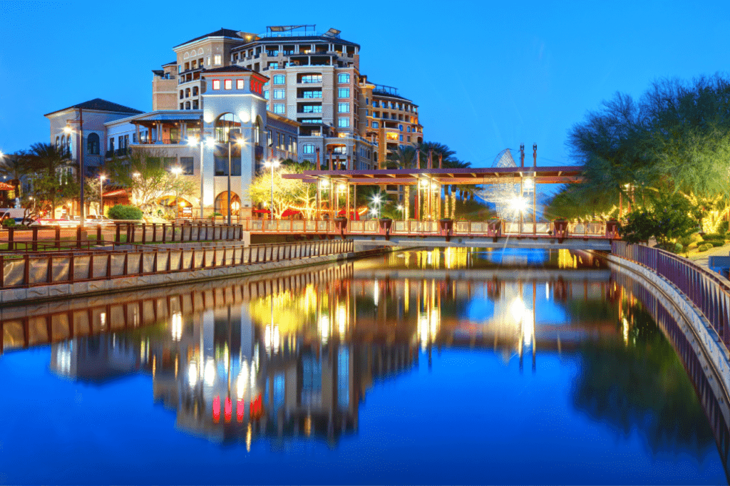 A canal in downtown Scottsdale in the evening. Lights from the buildings reflect off the water.