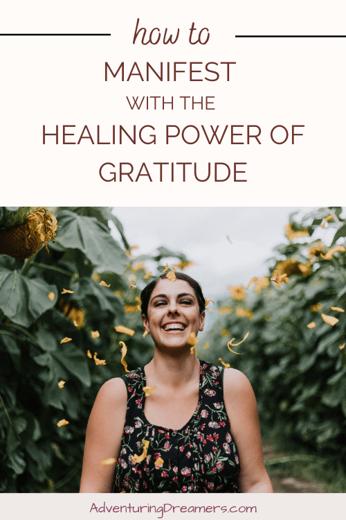 A woman smiles in a field of flowers while petals fly in the wind. Text reads, "How to manifest with the healing power of gratitude. Adventuringdreamers.com"