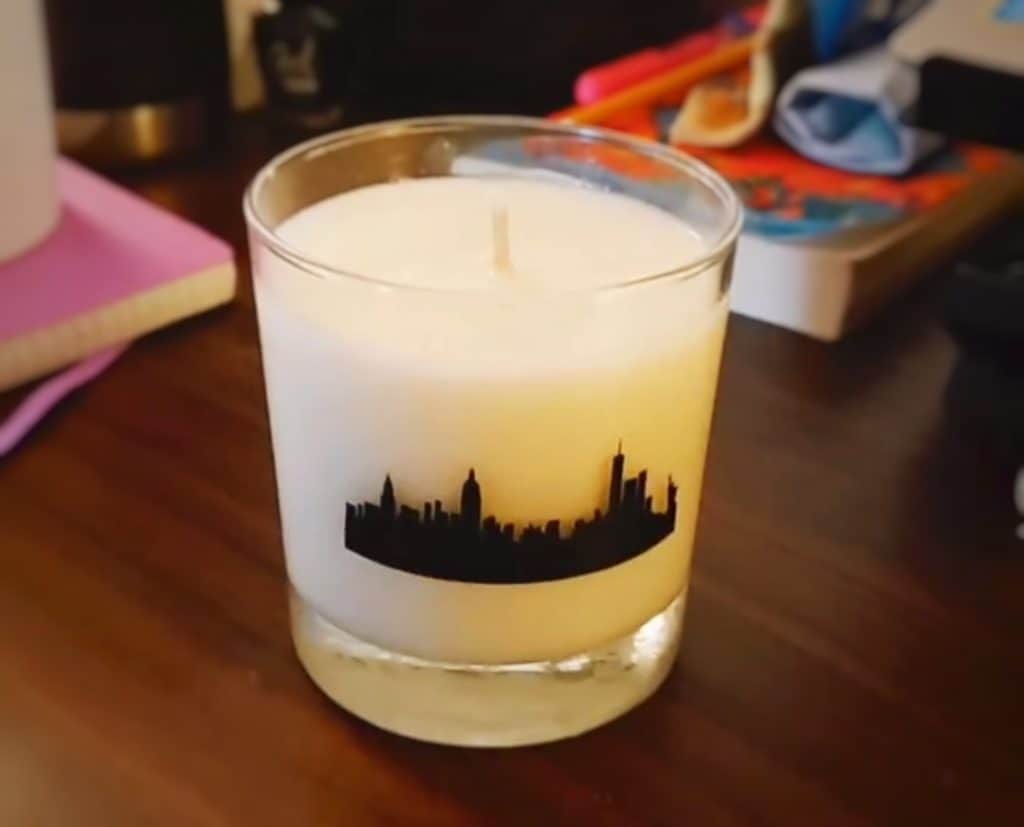 A candle with the New York City skyline printed on the glass.