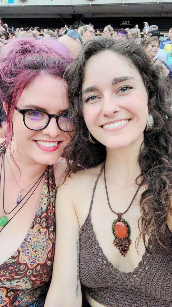 Two young women lean in close and smile for the camera.