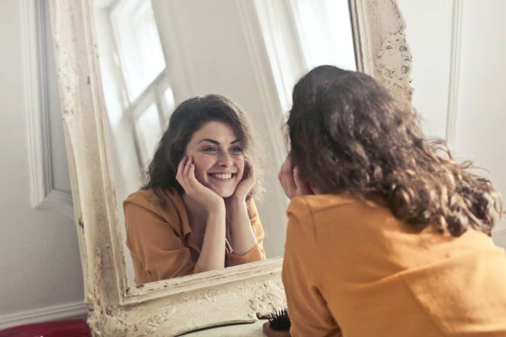 A woman smiles at herself in the mirror.