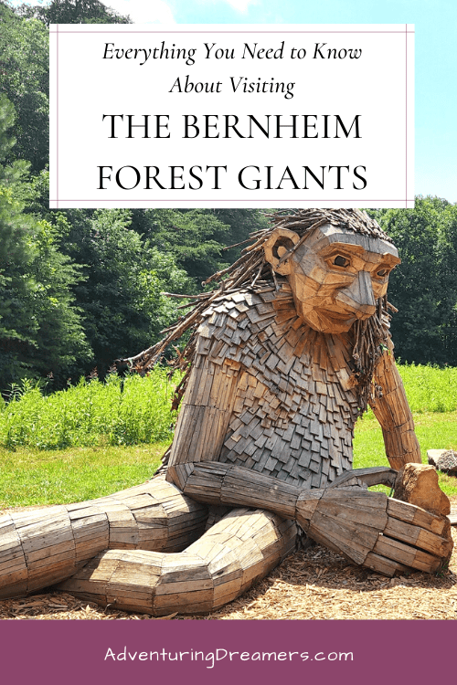A giant wooden sculpture of a troll playing with rocks. Text reads, "Everything you need to know about visiting the Bernheim Forest Giants. Adventuringdreamers.com"