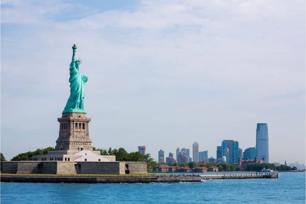 The Statue of Liberty stands in font of the skyline of NYC - which New York City pass is best to see the statue?