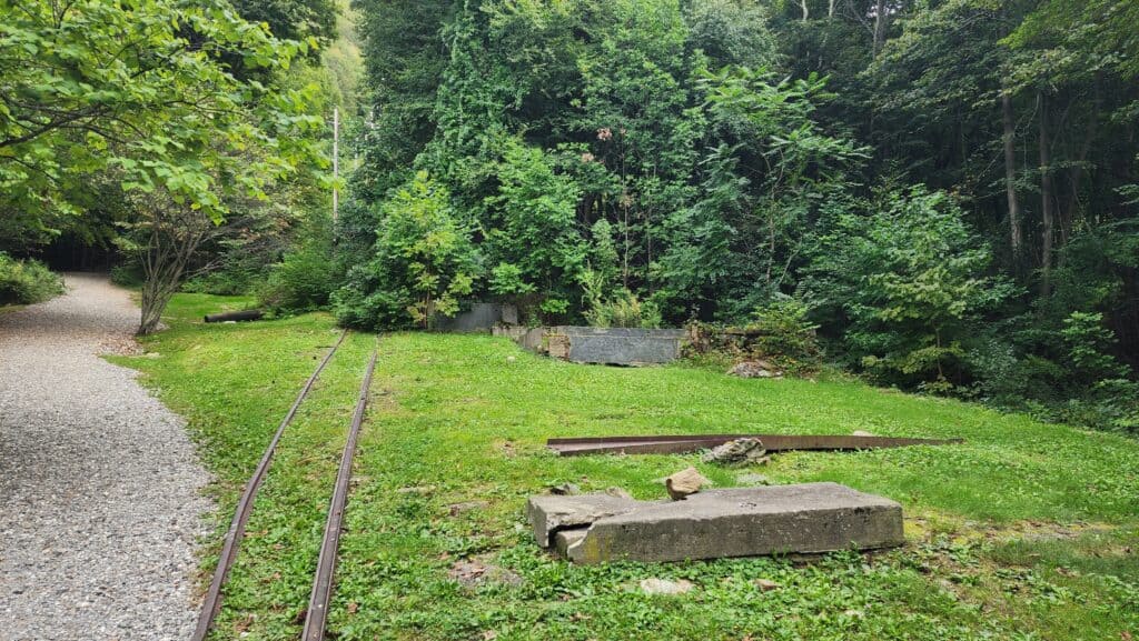 Abandoned railroad tracks cut across a grassy area.