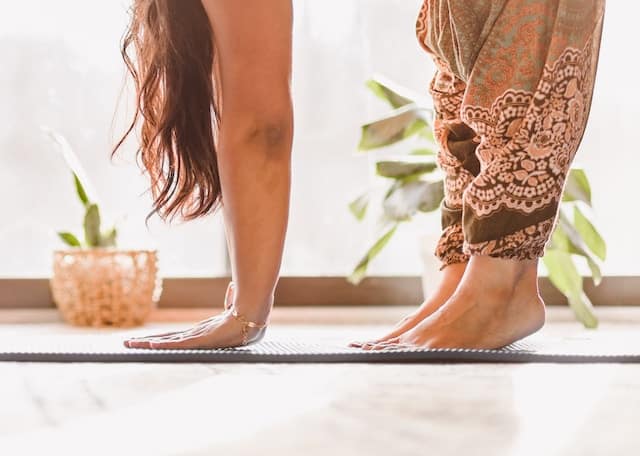 A woman with her hands and feet touching the yoga mat.