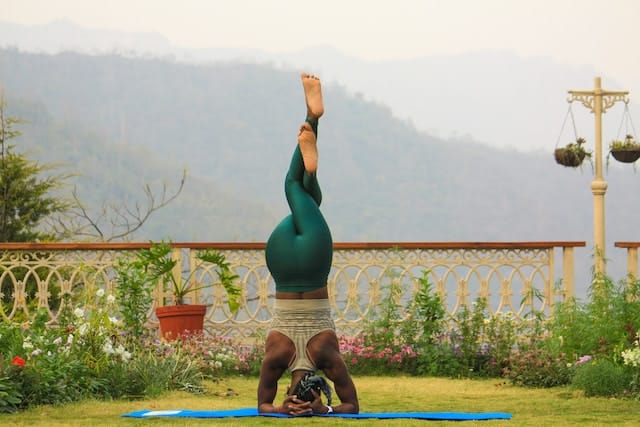 A woman does a twisted head stand yoga pose.