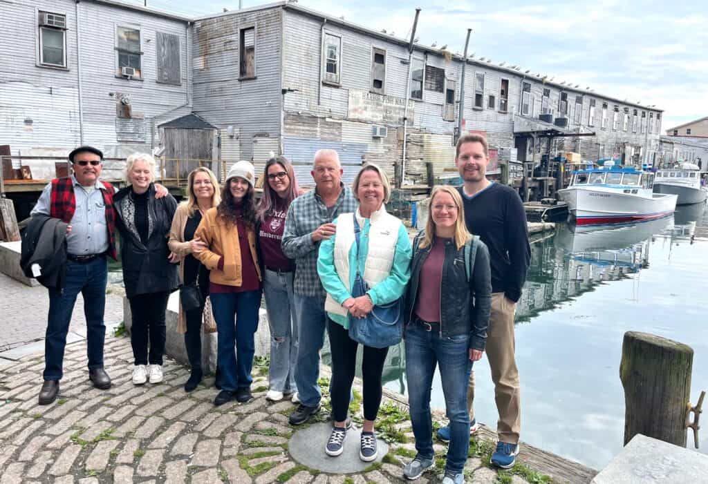 A group of people stand for a picture in front of a harbor.