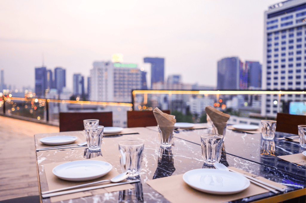 a table is set on a rooftop bar at dusk.