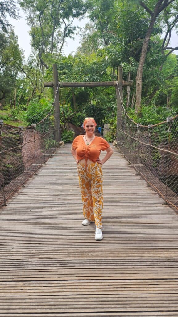 A woman stands on a bridge in a jungle.