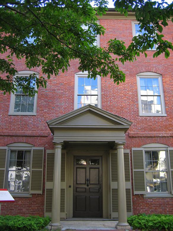 A colonial style brick building with pillars in front of the door.