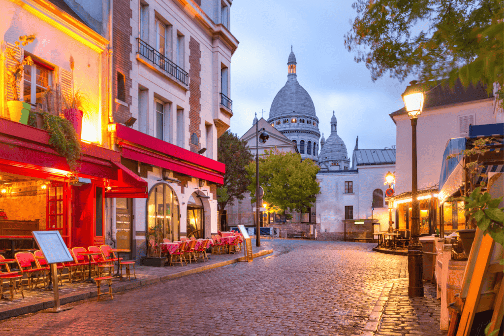 The Place du Tertre with tables of cafe and the Sacrre-Coeur in the early morning while the street lamps are still on.