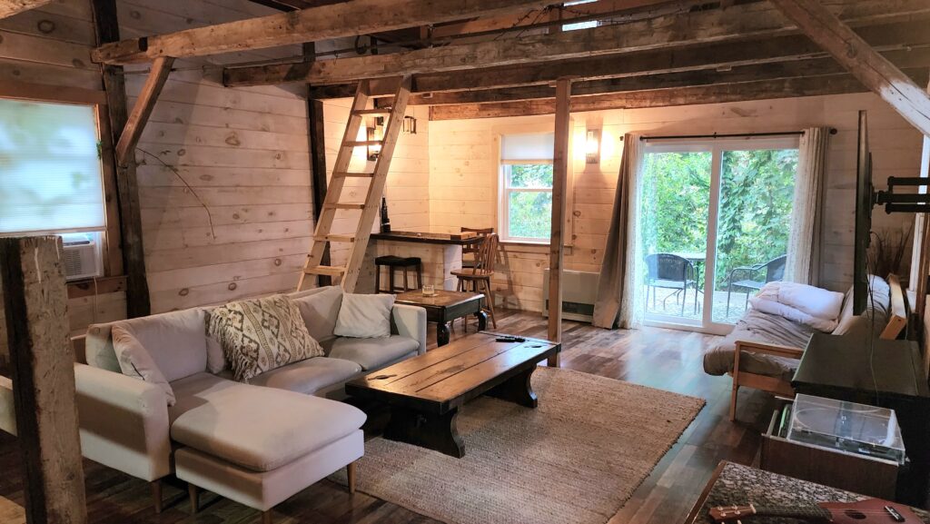 The rustic suite where I stayed in Portland, Maine. A living space with wooden rafters and a ladder leading up to a loft.