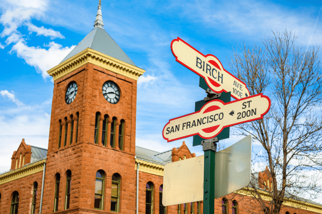Street signs posted on the corner in front of a building with a clock tower.