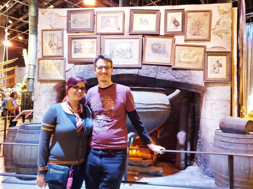 A man and woman stand in front of an exhibit of a large cauldron.