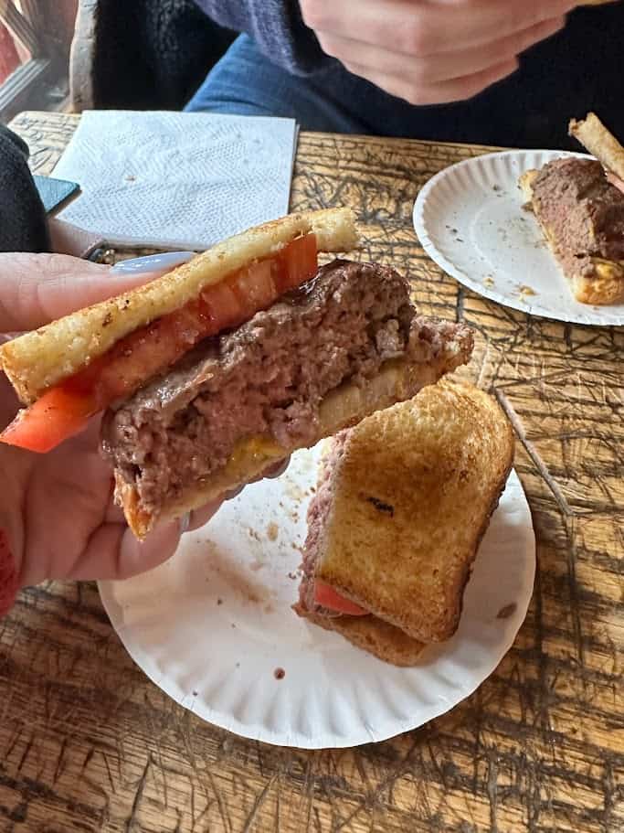 A meaty burger and tomato on sourdough bread.