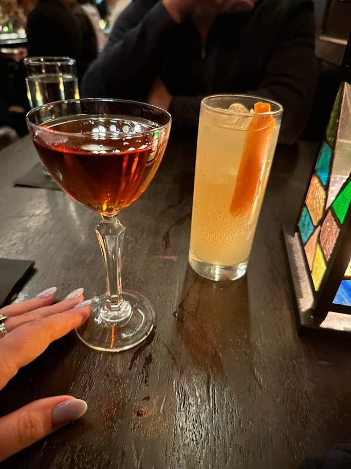 Two cocktails on a table at a bar.