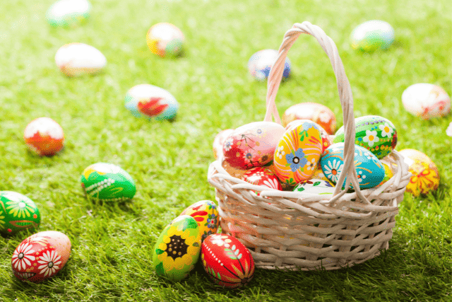 Decorated Easter eggs in a basket and on green grass.