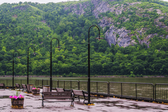Benches on a pier overlook a river and the mountains on the other side.