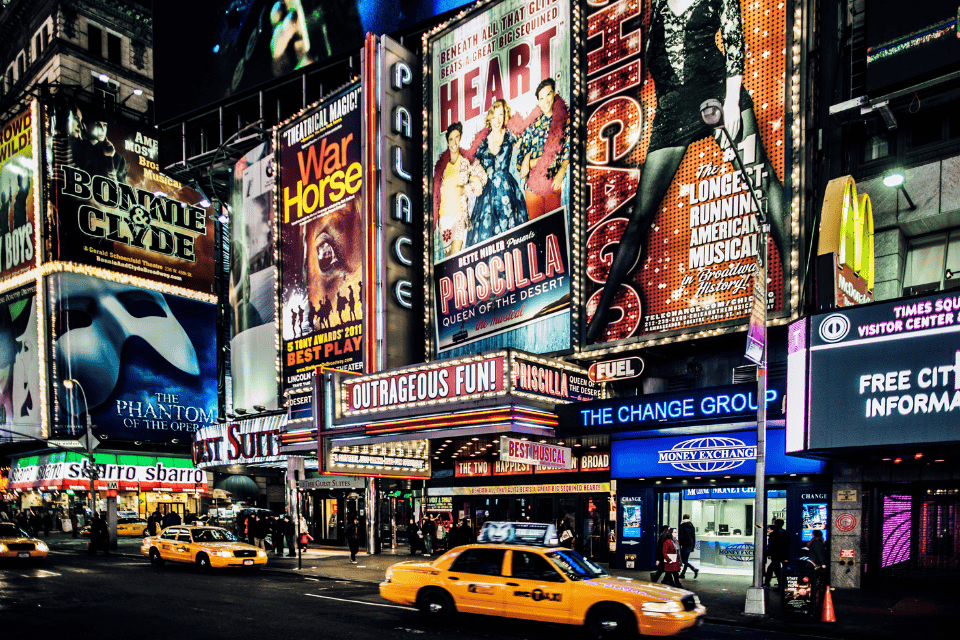 A street lined with billboards for famous plays and musicals.
